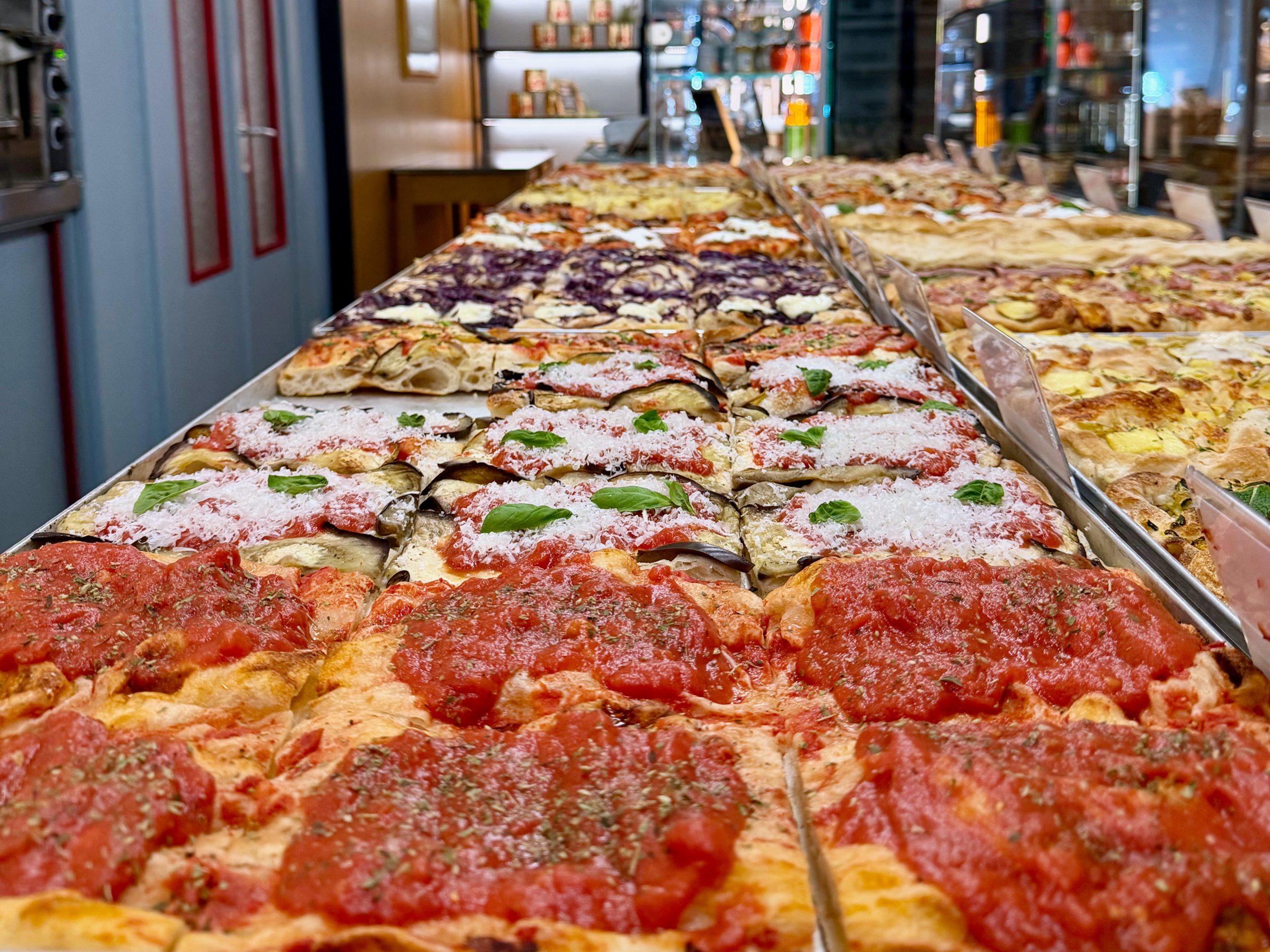 Bancone della pizzeria Staglio a Lugano con tranci di pizza al taglio appena sfornati Bancone della pizzeria Staglio a Lugano con tranci di pizza al taglio appena sfornati